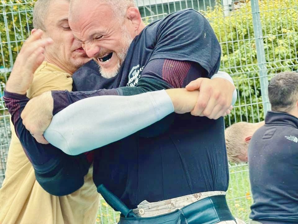 Two men working through heavy resistance during outdoor Kalah training