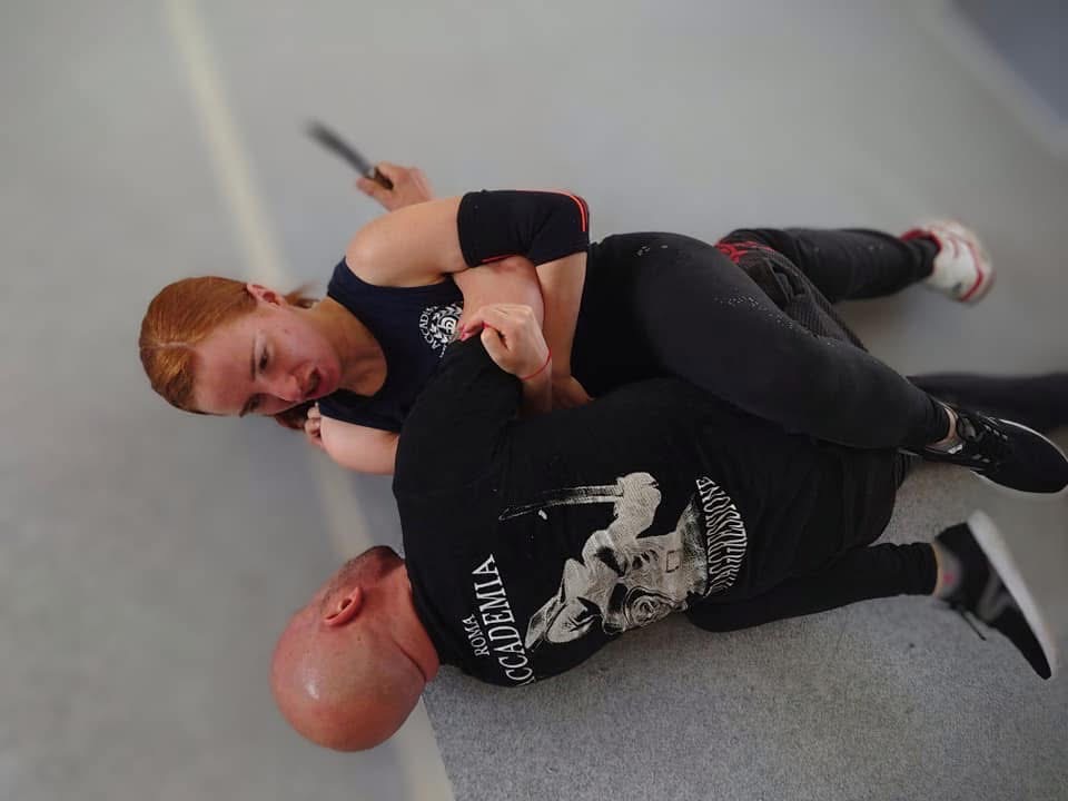 Two participants working through a knife-defense scenario on the gym floor